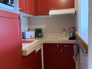 eine kleine Küche mit roten Schränken und einem Waschbecken in der Unterkunft Appartement Huez, 1 pièce, 4 personnes - FR-1-405-222 in Huez