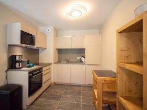 eine kleine Küche mit weißen Schränken und einer Mikrowelle in der Unterkunft Duplex 4 pièces avec balcon et parking, 6 pers. - Les Avanchers-Valmorel - FR-1-291-872 in Valmorel + 5 Fotos