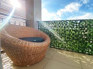 uma varanda com uma cadeira de vime e uma cerca verde em Residence Atlantic - Premium Apartment - WiFi, Gardien, Parking, Climaté em Douala