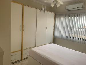 a bedroom with white cabinets and a bed with a window at Apartamento na Praia do Morro -160 metros da praia -Ar condicionado e internet -Perto de tudo in Guarapari