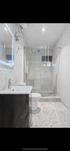 W łazience znajduje się prysznic, umywalka i toaleta. w obiekcie Kaf lag apartment w mieście Lekki