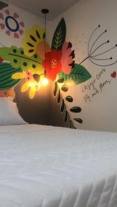 クイアバにあるTop Coliving Iの白いベッド1台、壁に花が描かれたベッドルーム1室