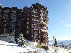 budynek w śniegu z choinką z przodu w obiekcie Studio 4 pers, Quartier des Jeux, Alpe d'Huez - Balcon exposé Sud, proche pistes et commerces - FR-1-405-225 w mieście LʼHuez