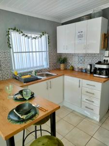 a kitchen with white cabinets and a wooden table at Adorable Garden Cottage In The Heart Of Pe in Lorraine