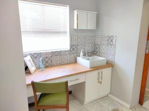 a bathroom with a sink and a green chair at Adorable Garden Cottage In The Heart Of Pe in Lorraine