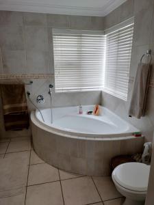 a bathroom with a tub and a toilet and a window at Holiday Home With Sea Views in Jeffreys Bay