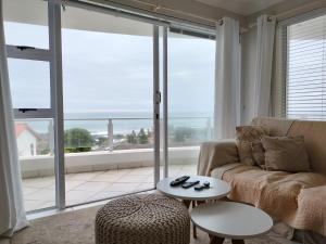 a living room with a couch and a table and a large window at Holiday Home With Sea Views in Jeffreys Bay