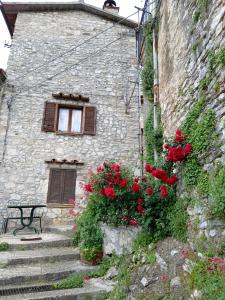 un edificio de piedra con una ventana y flores rojas en casa belvedere a Valle San Martino di Spoleto en Spoleto