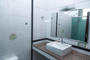 uma casa de banho branca com um lavatório e um espelho em Hotel Equinocios Executive em Barcarena