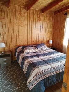 Bett in einem Zimmer mit holzgetäfelten Wänden in der Unterkunft Cabaña en Chacao Viejo, Chiloé - Tranquilidad y Frente al mar in Ancud