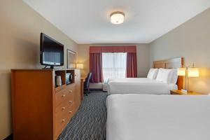 a hotel room with two beds and a flat screen tv at Best Western Grande Prairie in Grande Prairie