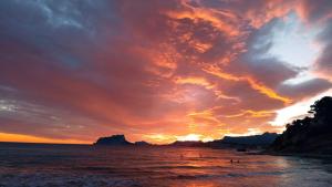 a sunset on the beach with people in the water at Paraíso in Cumbre del Sol