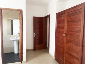 uma casa de banho com uma porta de madeira e um lavatório em Residence Atlantic - Premium Apartment - WiFi, Gardien, Parking, Climaté em Douala