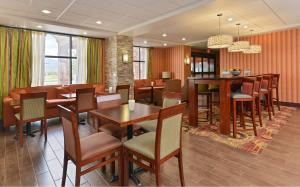 a restaurant with tables and chairs and a bar at Hampton Inn Muscatine in Muscatine