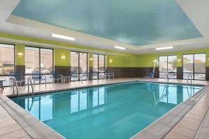una piscina en una habitación de hotel con mesas y sillas en Hampton Inn & Suites Mishawaka/South Bend at Heritage Square, en South Bend