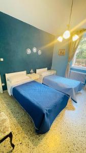 two beds in a bedroom with blue walls at Domi B & B in Macerata