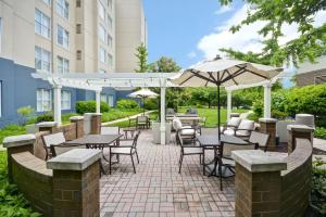 un patio al aire libre con mesas, sillas y sombrillas en Homewood Suites Dulles-International Airport, en Herndon