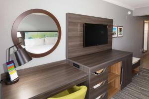 a living room with a television and a mirror at Hampton Inn Saint Augustine Beach in Saint Augustine Beach