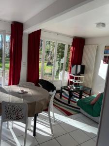 un soggiorno con tende rosse, tavolo e sedie di Les Argousiers a Le Touquet-Paris-Plage