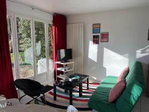 a living room with a green couch and a tv at Les Argousiers in Le Touquet-Paris-Plage