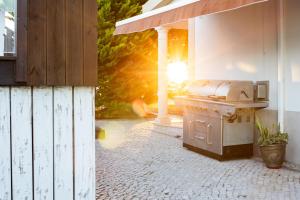 a grill on a patio with the sun in the background at KABACEIRA VILLAGE in Atalaia