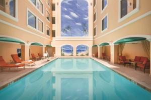 a swimming pool in a building with chairs and tables at Hilton Los Angeles/San Gabriel in San Gabriel