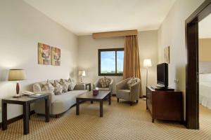 a hotel room with a couch and a tv and a bed at Hilton Garden Inn Riyadh Olaya in Riyadh