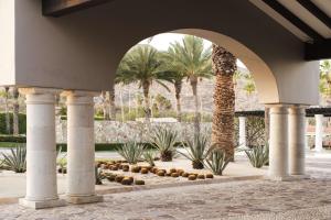 an archway with palm trees and a fountain at Hilton Los Cabos in San José del Cabo