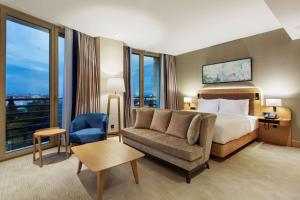 イスタンブールにあるダブルツリー バイ ヒルトン ホテル イスタンブール トゥズラのベッド、ソファ、窓が備わるホテルルームです。