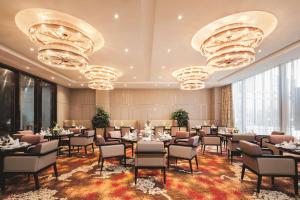 a dining room with tables and chairs and chandeliers at DoubleTree By Hilton Anhui in Suzhou