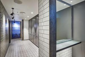 uma cabina de duche ao nível do chão numa casa de banho com azulejos brancos em Canopy by Hilton Reykjavik City Centre em Reykjavík
