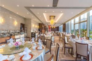 un restaurante con mesas y sillas blancas y ventanas en Hilton Garden Inn Hong Kong Mongkok, en Hong Kong