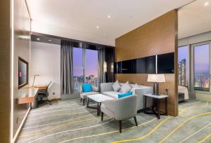 een hotelkamer met een bank en een bureau bij Hilton Garden Inn Hong Kong Mongkok in Hong Kong