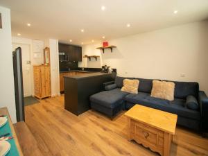 Una sala de estar con un sofá azul y una cocina. en Charmant 2 pièces pour 5 pers avec balcon, service linge inclus ! - FR-1-291-877, en Valmorel