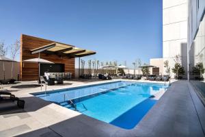 a swimming pool with chairs and a building at Hilton Garden Inn Aguascalientes in Aguascalientes