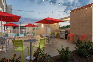 a patio with tables and chairs and red umbrellas at Home2 Suites By Hilton Savannah Airport in Savannah