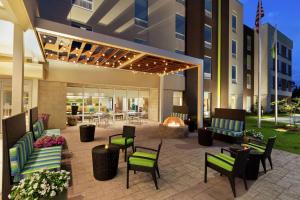 a patio with chairs and a fire place in front of a building at Home2 Suites By Hilton Savannah Airport in Savannah
