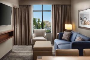 Embassy Suites by Hilton South Bend في ساوث بند: غرفة معيشة مع أريكة وكرسي وتلفزيون