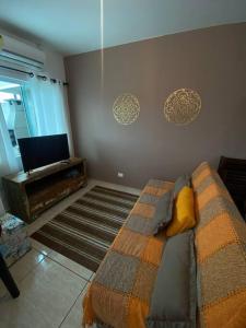 a living room with a bed and a television at Casa a poucos metros da praia! in Guaratuba