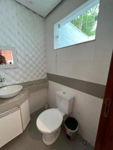 a bathroom with a toilet and a sink and a window at Villa dos Diamantes - 16 in Porto Seguro