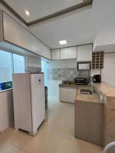 a large kitchen with a refrigerator and a sink at Villa dos Diamantes - 16 in Porto Seguro