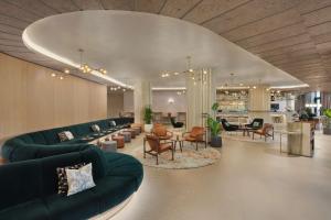 Canopy by Hilton London City في لندن: غرفة معيشة مع كنب وطاولات وكراسي