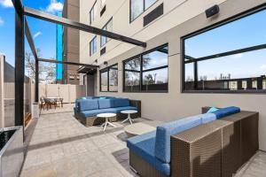 patio z niebieskimi kanapami, stołami i oknami w obiekcie Tru By Hilton Portland Airport, Or w mieście Portland