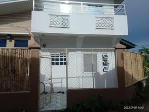 ein Haus mit einer weißen Tür und einem Zaun in der Unterkunft Budget room with split type air-condition in San Fernando