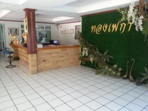 a restaurant with a green wall and a counter at Thong Paeka Hotel in Prasat