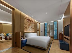 DanzhouにあるHilton Hainan Ocean Flower Islandのベッドルーム(白いベッド1台付)、リビングルームが備わります。