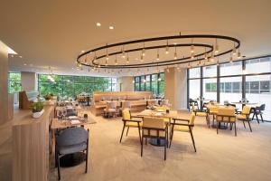 restauracja ze stołami i krzesłami oraz dużym żyrandolem w obiekcie Hilton Garden Inn Seoul Gangnam w Seulu