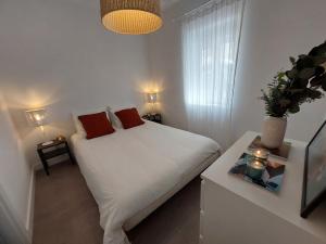 1 dormitorio con 1 cama blanca y 2 almohadas rojas en Cosy, Stylish, Central en Lisboa