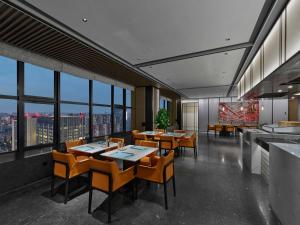 um restaurante com mesas, cadeiras e janelas em DoubleTree By Hilton Chengdu Riverside em Chengdu