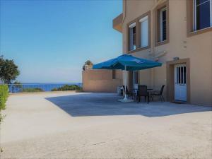 a patio with a blue umbrella next to a building at Afentis Apartment in Chios